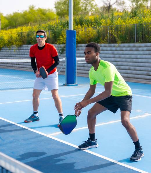 Full length photo of a multiracial team of pickleball players in an outdoor court in a sunny day